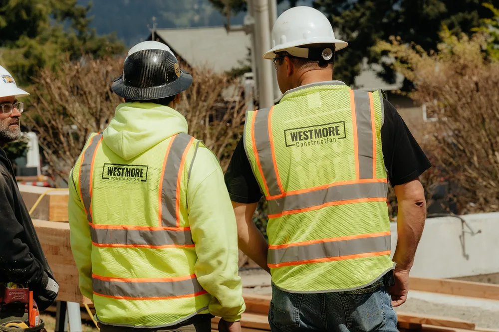 Two Westmore crew members from behind in WESTMORE vests at a timber job