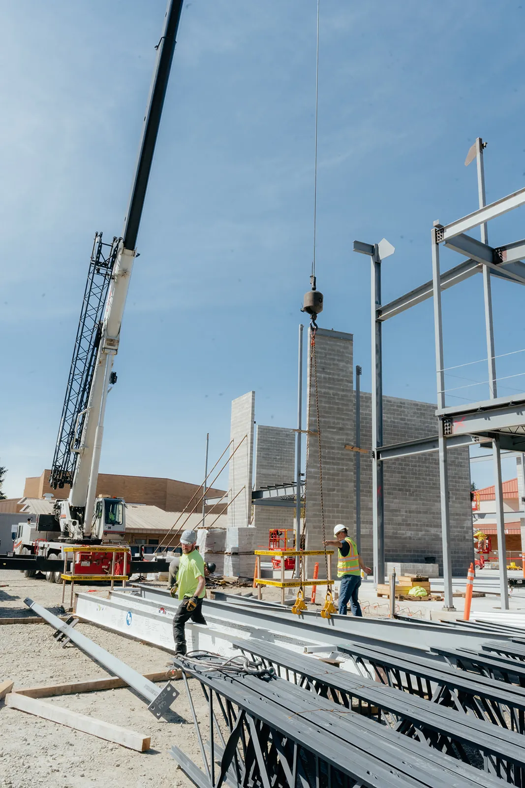 Crane hook line above steel columns with bar joists staged on the ground