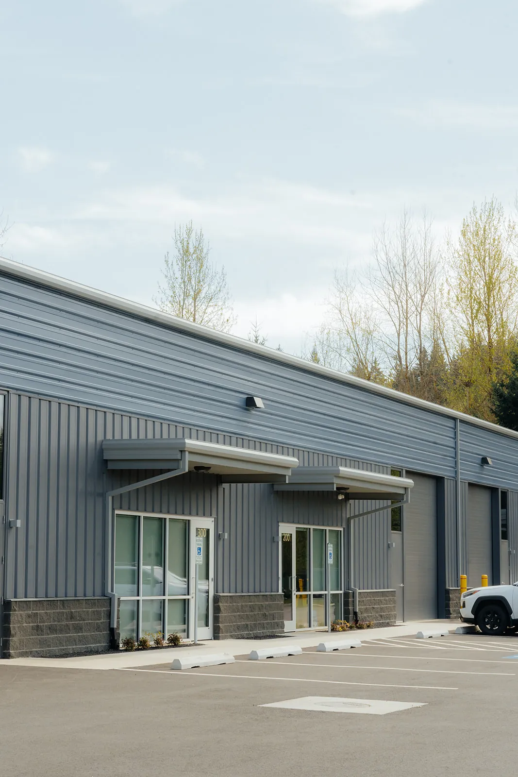 Side view of a completed gray metal commercial building with windows and downspouts