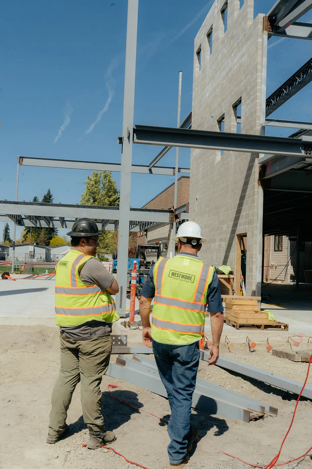 Two Westmore crew members walking through a steel column and beam frame with CMU walls