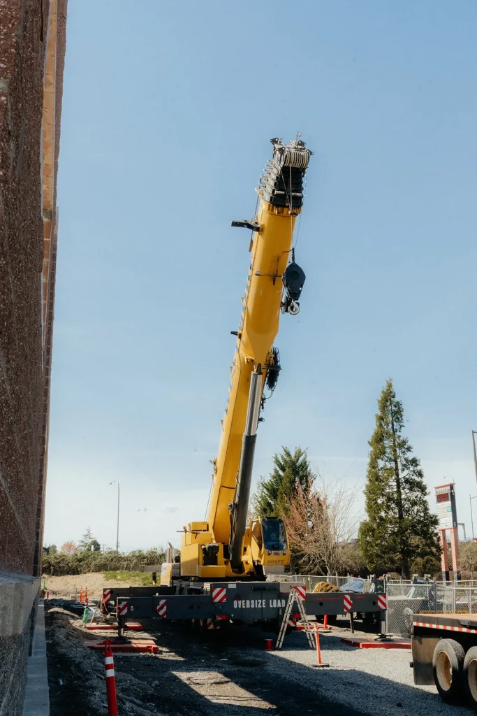Westmore yellow Grove crane set up on a street with traffic cones beside a brick building